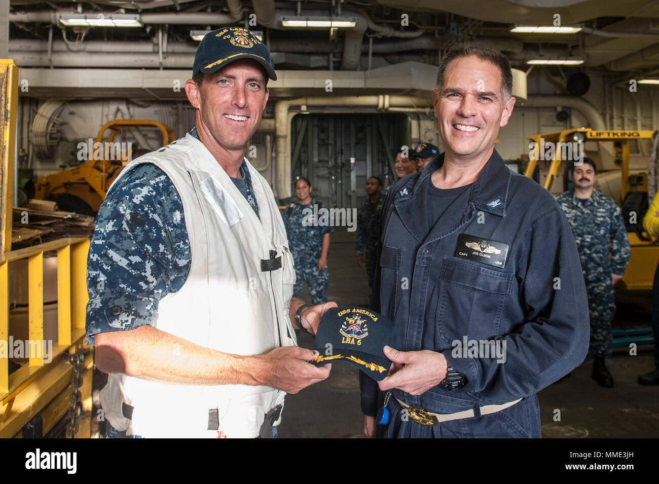 171024-N-ZS023-061 5TH FLEET AREA OF OPERATIONS (Oct. 24, 2017) Captain Joseph Olsen, the Commanding Officer of the amphibious assault ship USS America (LHA 6), and Captain Darren McPherson, the Commanding Officer of the Ticonderoga-class guided-missile cruiser USS Lake Erie (CG 70), pose for a photo in the America’s vehicle storage area. America is the flagship for the America Amphibious Ready Group and, with the embarked 15th Marine Expeditionary Unit, is deployed to the U.S. 5th Fleet area of operations in support of maritime security operations to reassure allies and partners and preserve  Stock Photo