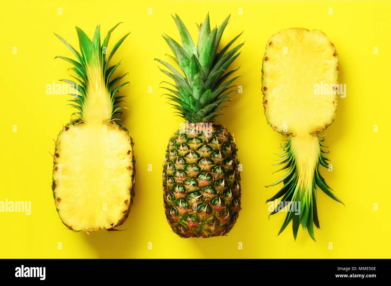 Half slice of fresh pineapple and whole fruit on yellow background. Top ...