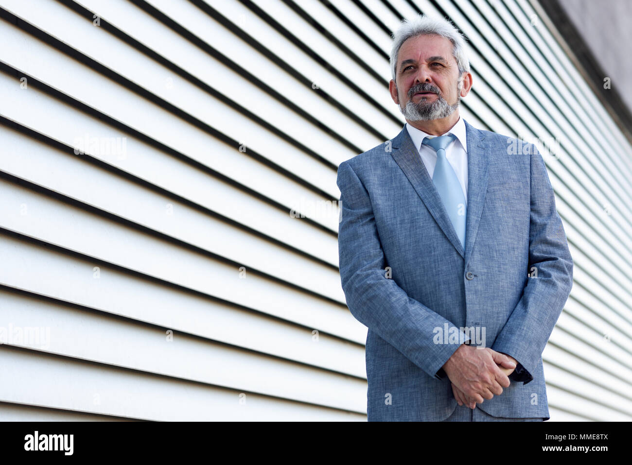 Portrait of a senior businessman with arms crossed outside of modern ...