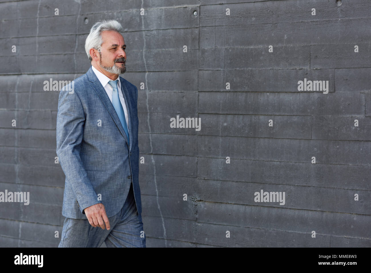 Senior businessman walking outside of modern office building ...