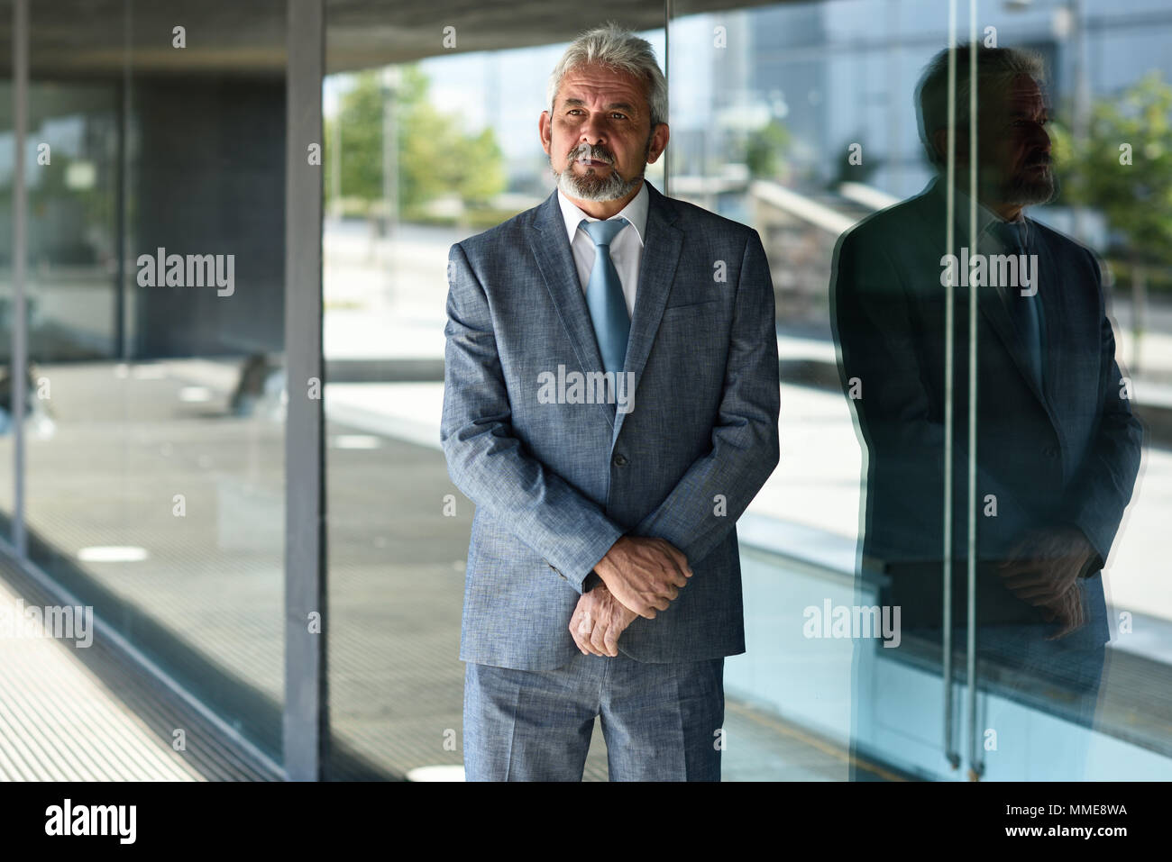 Portrait of a senior businessman with arms crossed outside of modern ...