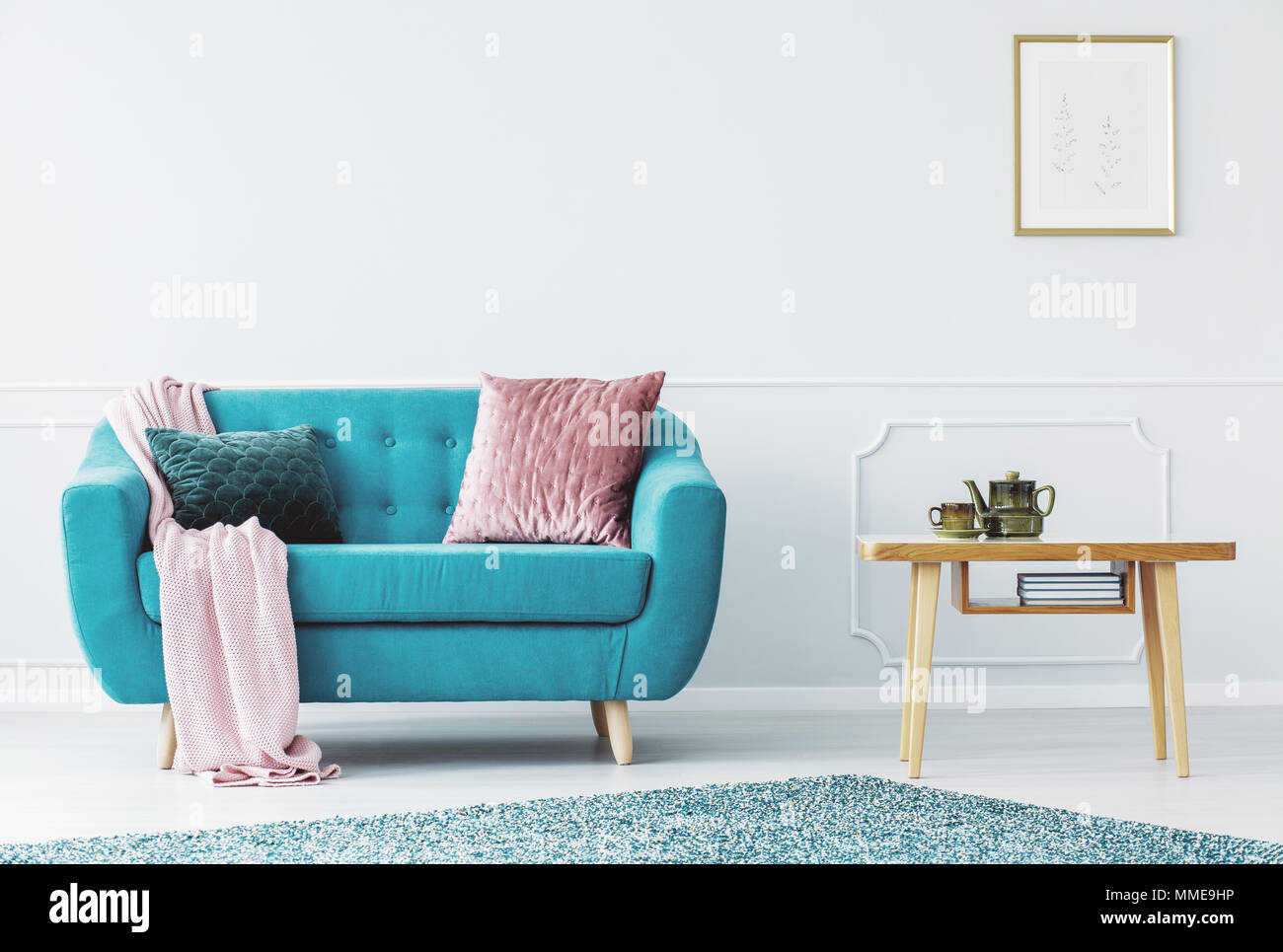 Blue sofa with pastel pink blanket and two pillows standing in bright  living room interior with wall molding Stock Photo - Alamy