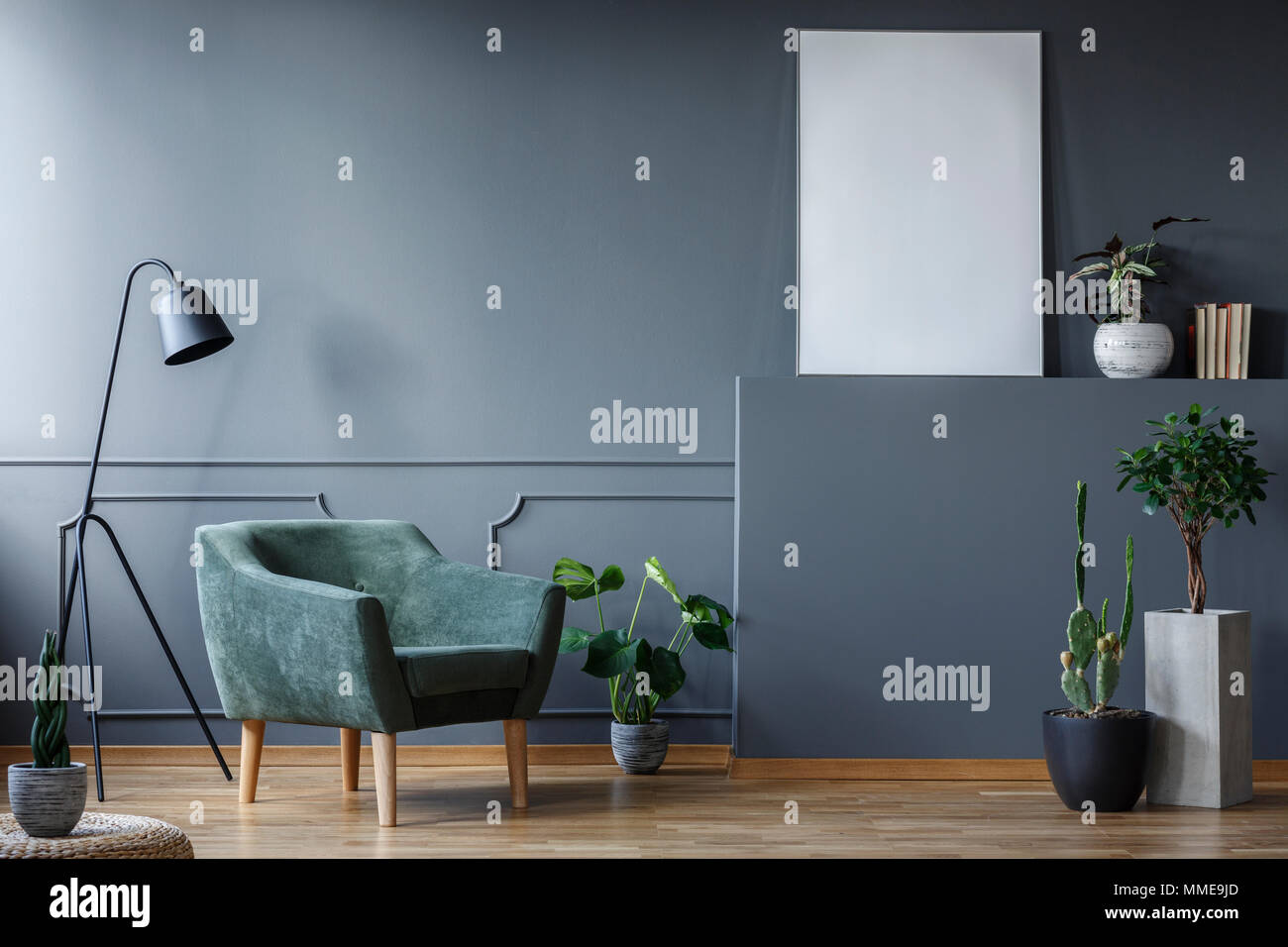 Black lamp next to green armchair in living room interior with plants ...