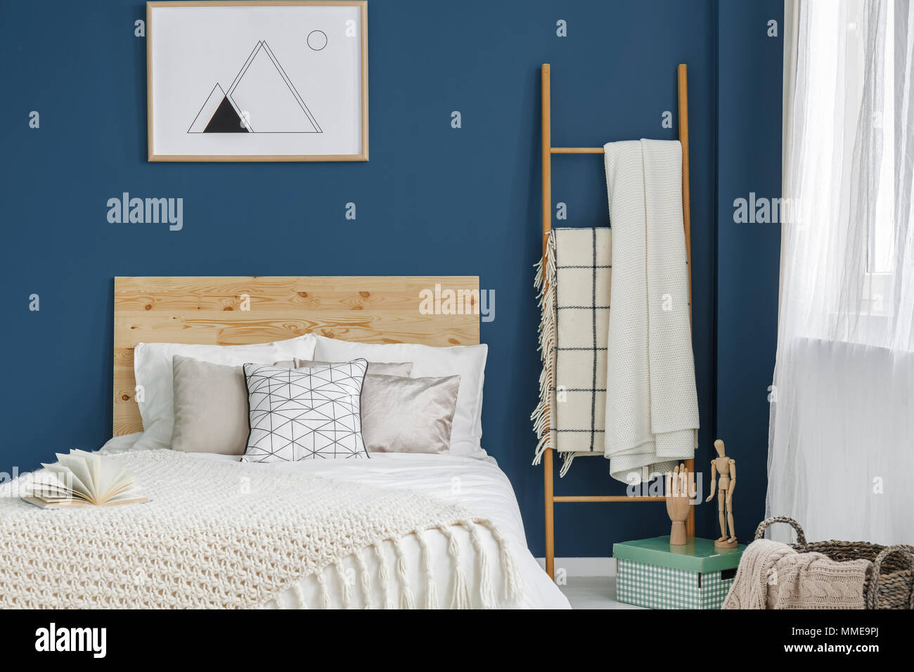 Double bed with wooden bedhead standing in blue room interior with