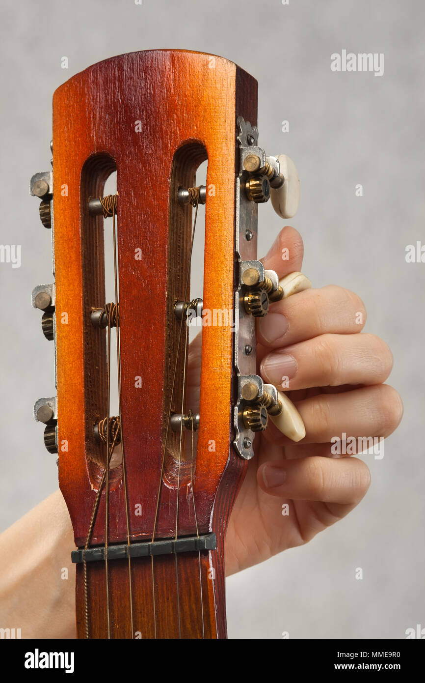 closeup of hands tuning acoustic guitar from headstock Stock Photo