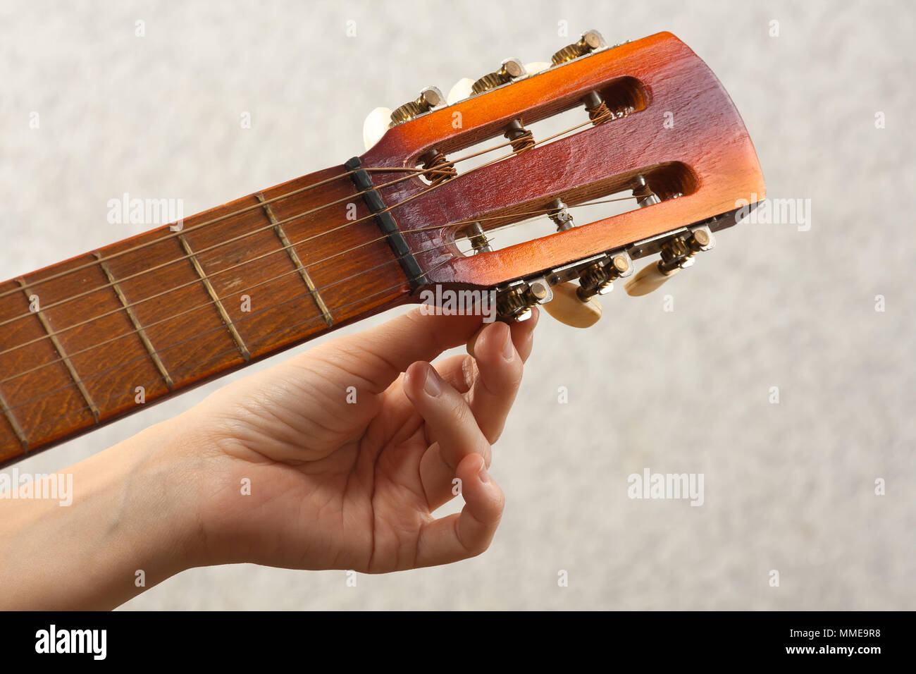 hand tuning acoustic guitar from headstock, closeup Stock Photo