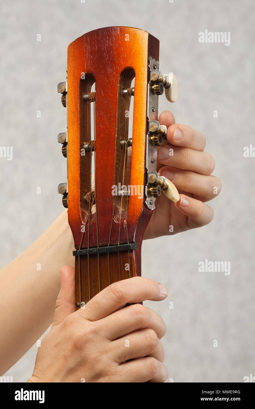 hands of guitarist tuning acoustic guitar from headstock Stock Photo