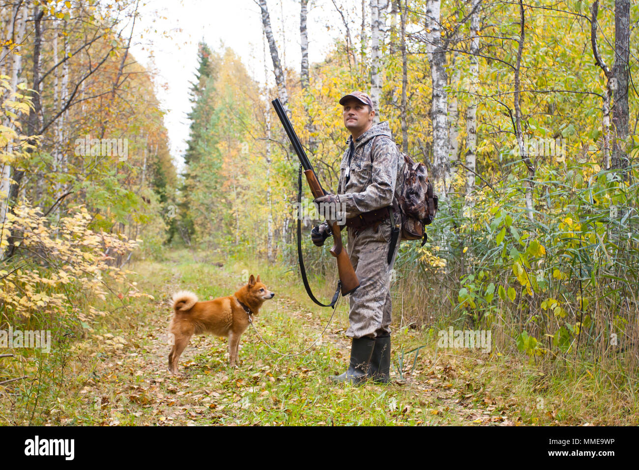 hunter with hunting gun and dog in the autumn forest Stock Photo