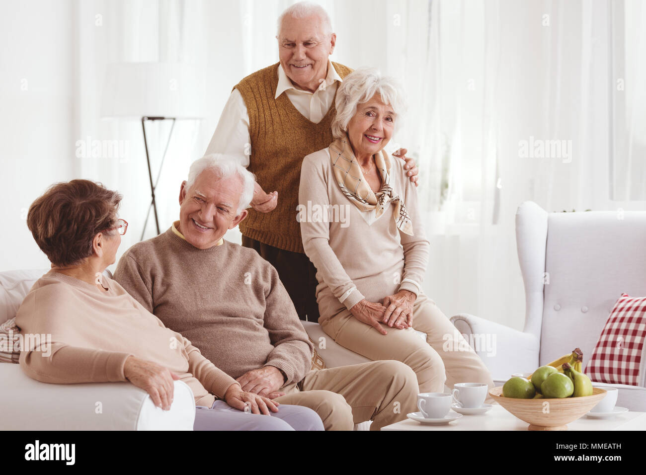 Two senior couples relaxing together at home, talking and smiling Stock Photo