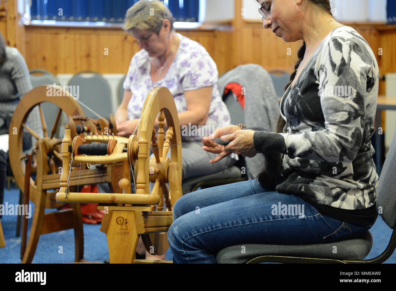 Spinners and weaver working on spinning wheels making yarn at the