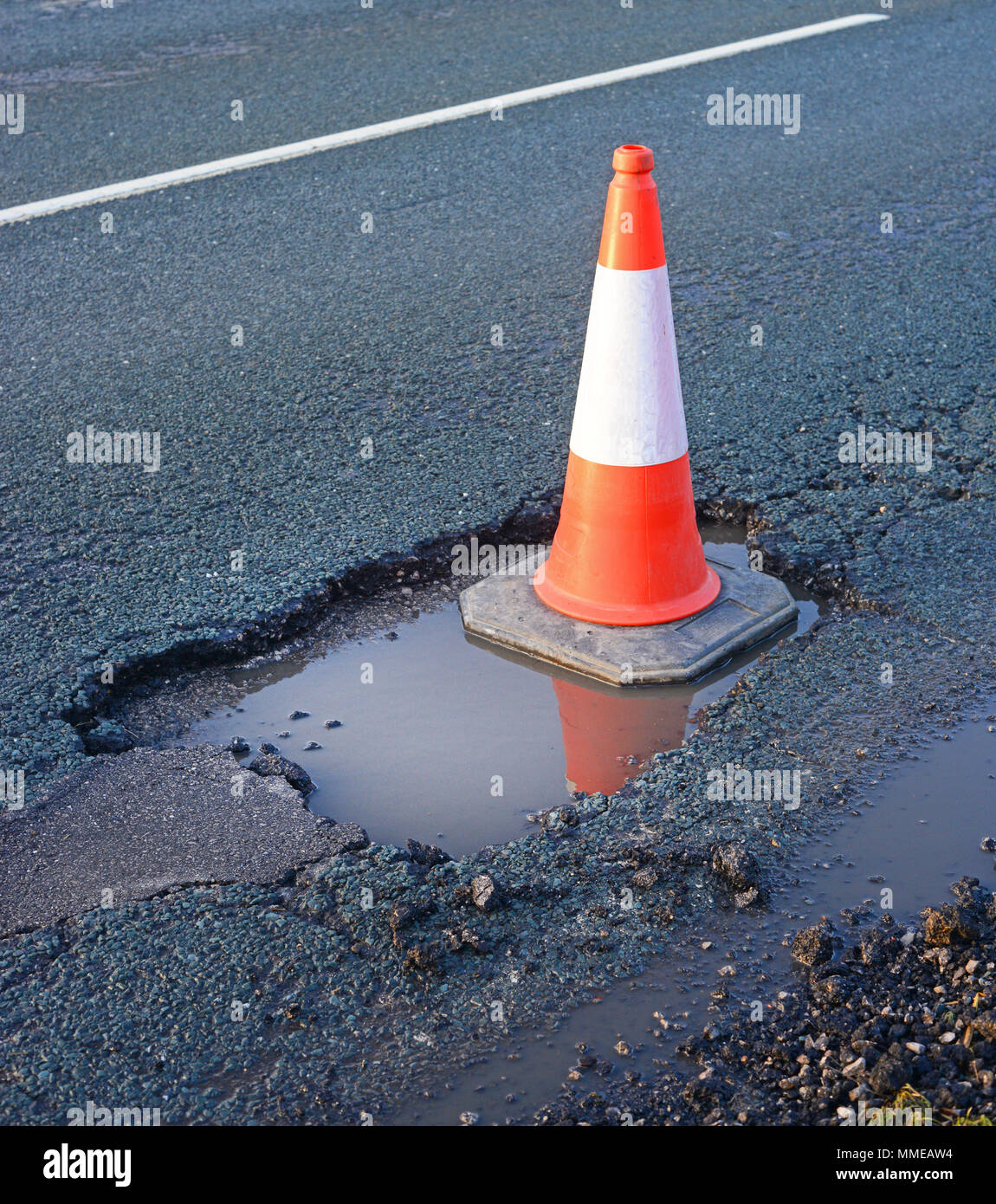 traffic cone marking giant water filled pothole on road york yorkshire united kingdom Stock Photo