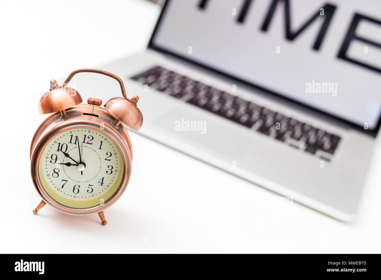 office table with time on screen laptop, and vintage alarm clock on white background Stock Photo