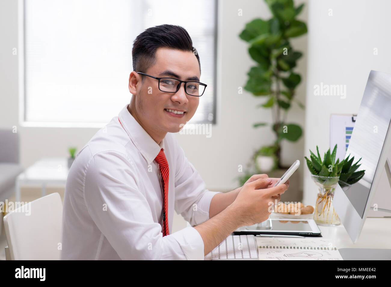 Man using computer and smart phone at the table in office against the window Stock Photo