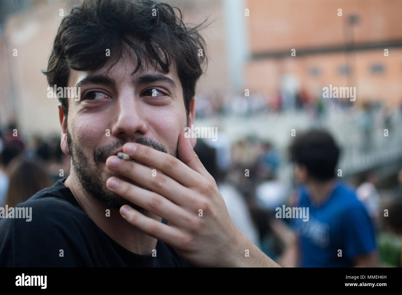 front view of an Italian young man smoking a cigarette or a legal joint, marijuana or tobacco Stock Photo