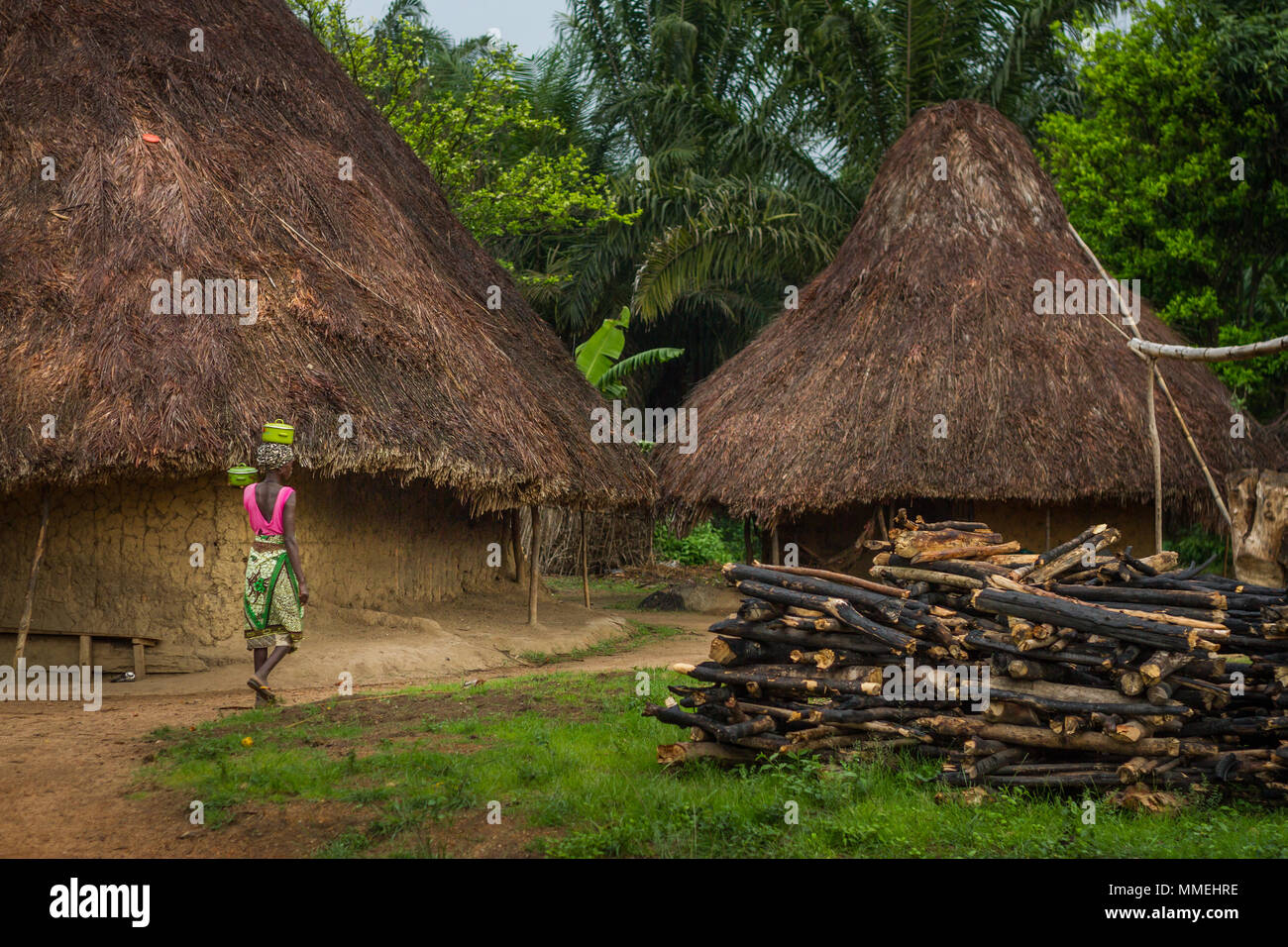 YONGORO, SIERRA LEONE - June 06, 2013: West Africa, unknown woman carries a pot on the head next to the village huts near the capital Freetown, Sierra Stock Photo