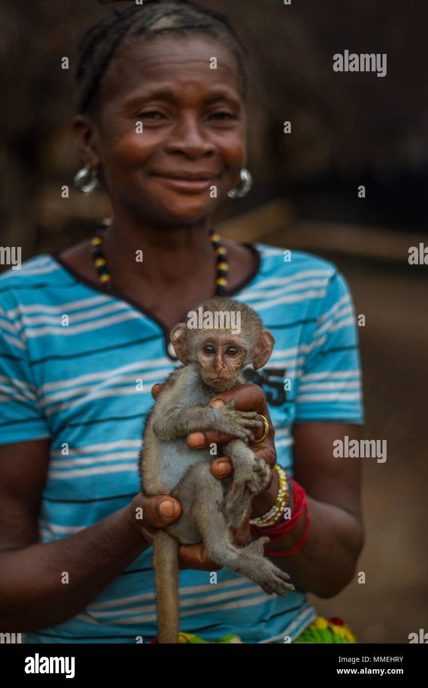 YONGORO, SIERRA LEONE - June 06, 2013: West Africa, portrait of unknown woman with a little monkey saved from the forest near the capital Freetown, Si Stock Photo