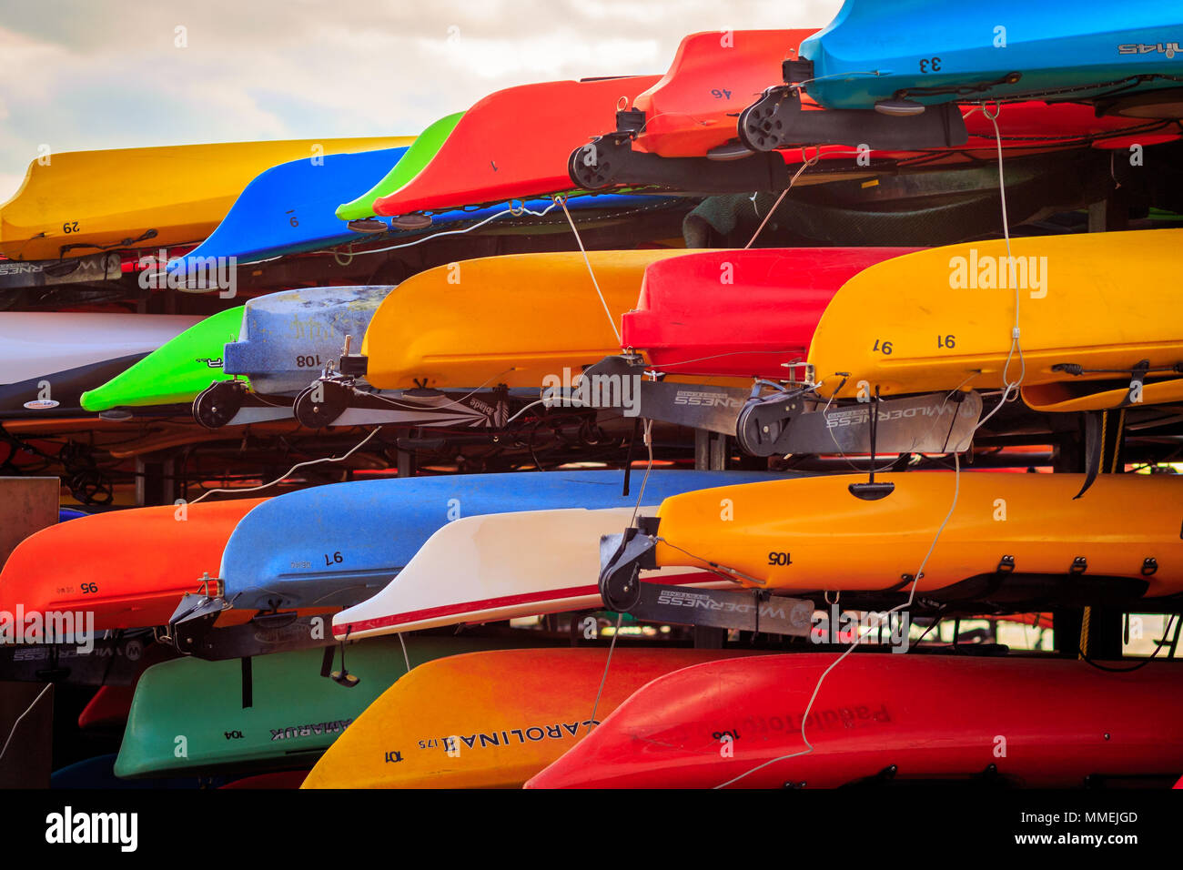 a collection of upturned canoes of differing colours stacked up on the