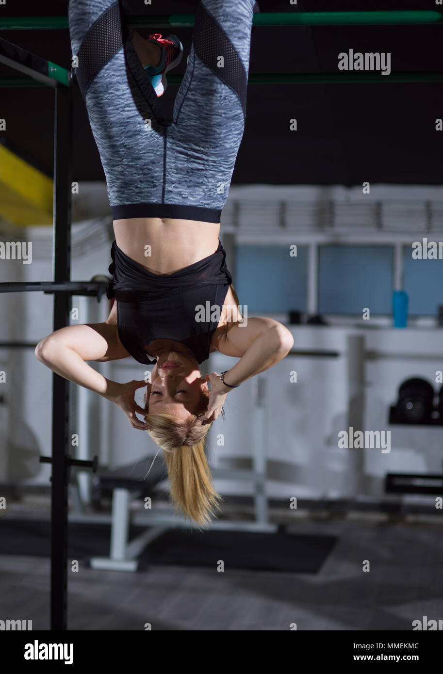 athlete woman doing abs exercises hanging upside down on horizontal bar