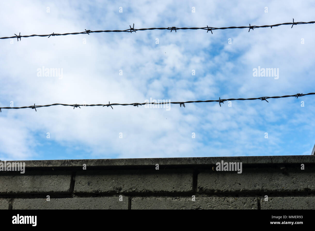 Barbed wire fence against the blue sky with clouds Stock Photo - Alamy