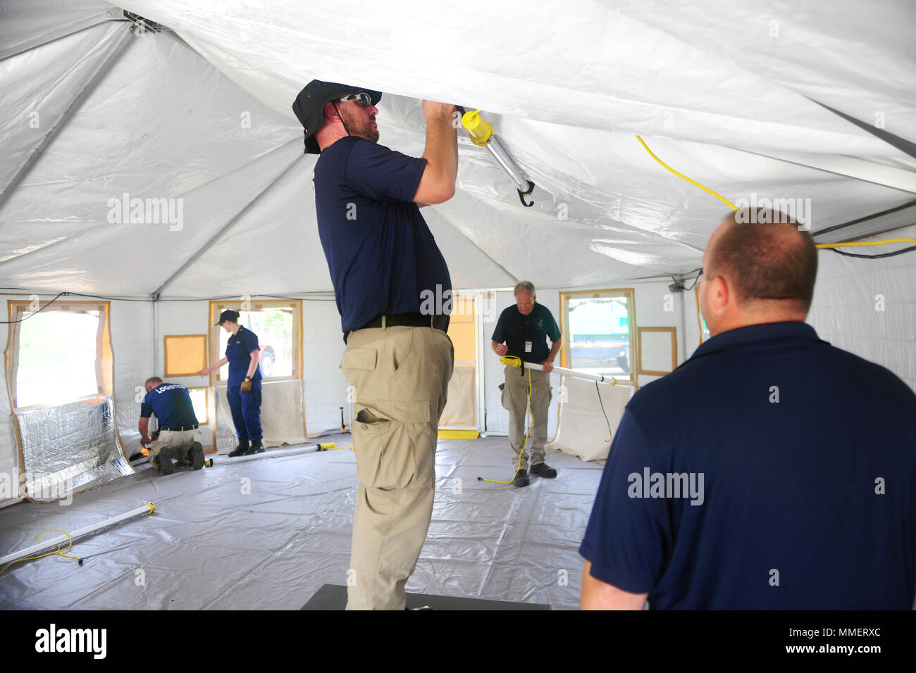 VIEQUES, Puerto Rico – Joshua Gore, U.S. Department of Health and Human  Services logistics, installs lighting inside a Western Shelter tent being  erected outside the Puerto Rican island-municipality of Vieques' sole  hospital