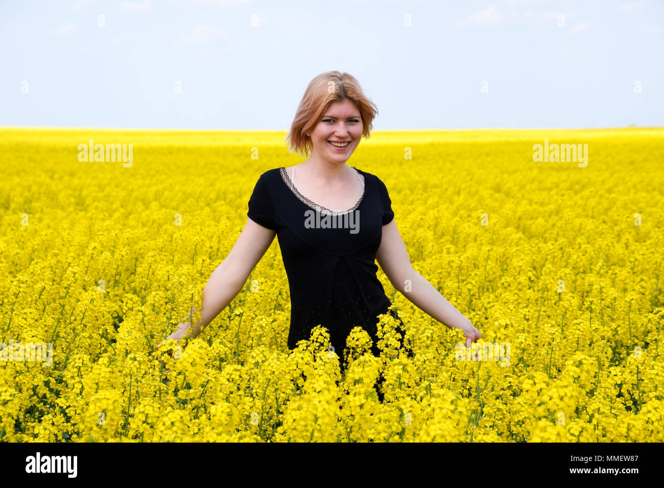 A girl in a black dress in a field of flowering rape Stock Photo - Alamy
