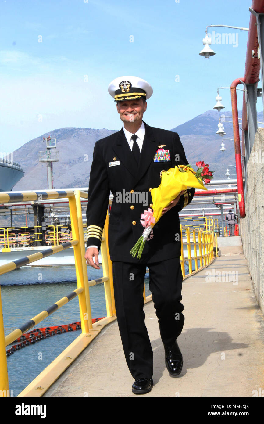 172027-N-QM497-001 GAETA, Italy (Oct. 27, 2017) Capt. Kavon Hakimzadeh, commanding officer of the Blue Ridge-class amphibious command ship USS Mount Whitney (LCC 20) carries a bouquet of flowers for his wife following the ship’s arrival at its forward-deployed port of Gaeta, Italy Oct. 27, 2017. Mount Whitney, the U.S. 6th Fleet flagship, operates with a combined crew of U.S. Navy Sailors and Military Sealift Command civil service mariners. (U.S Navy photo by Interior Communications Electrician 3rd Class Rebeca Gibson/Released) Stock Photo