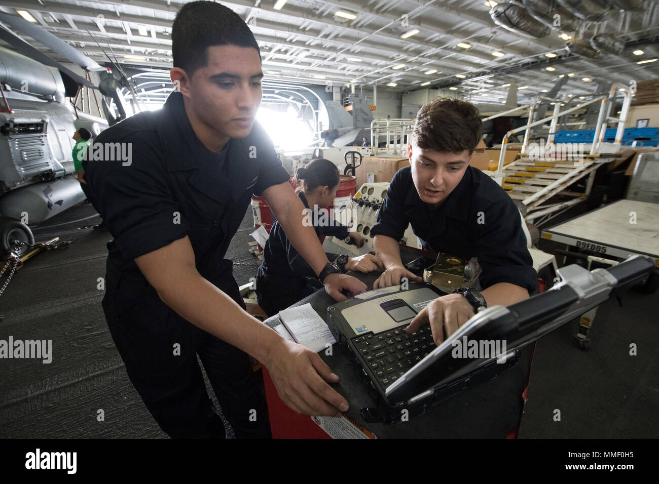 USS Carl Vinson (CVN-70) is a Nimitz-class nuclear-powered aircraft carrier commissioned in 1982. The archival image records aviation support personnel using a Portable Electronic Maintenance Aid system within the hangar bay during sustainment training operations in the Pacific Ocean in 2017. Stock Photo