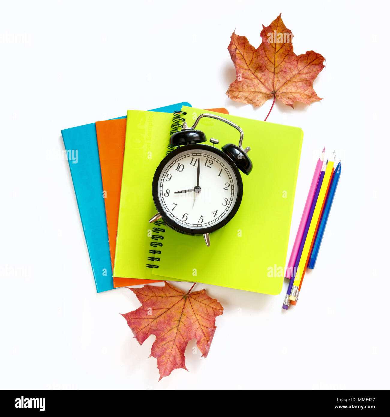 Colorful school supplies, notebooks and alarm clock on white. Top view