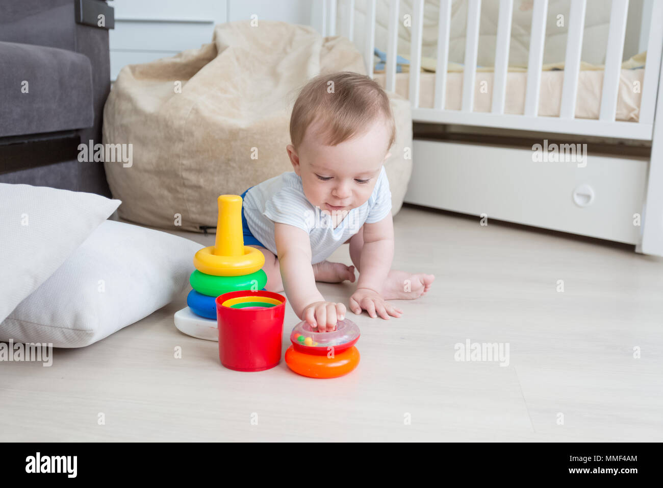 Adorable 10 months old toddler boy p laying in educaitonal games on floor Stock Photo