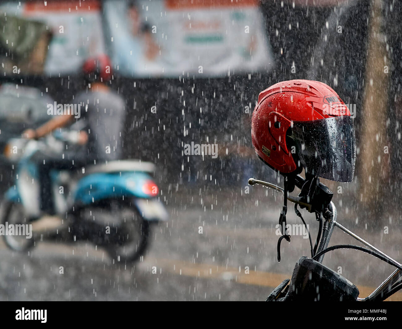Riding motorbike rain. Motorbike in torrential rainfall. Thailand monsoon season. Southeast Asia. motorcycle helmet red Stock Photo
