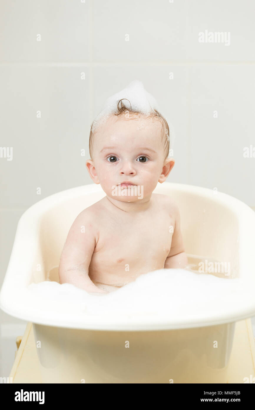 Portrait of cute toddler boy washing in bath full of foam Stock Photo