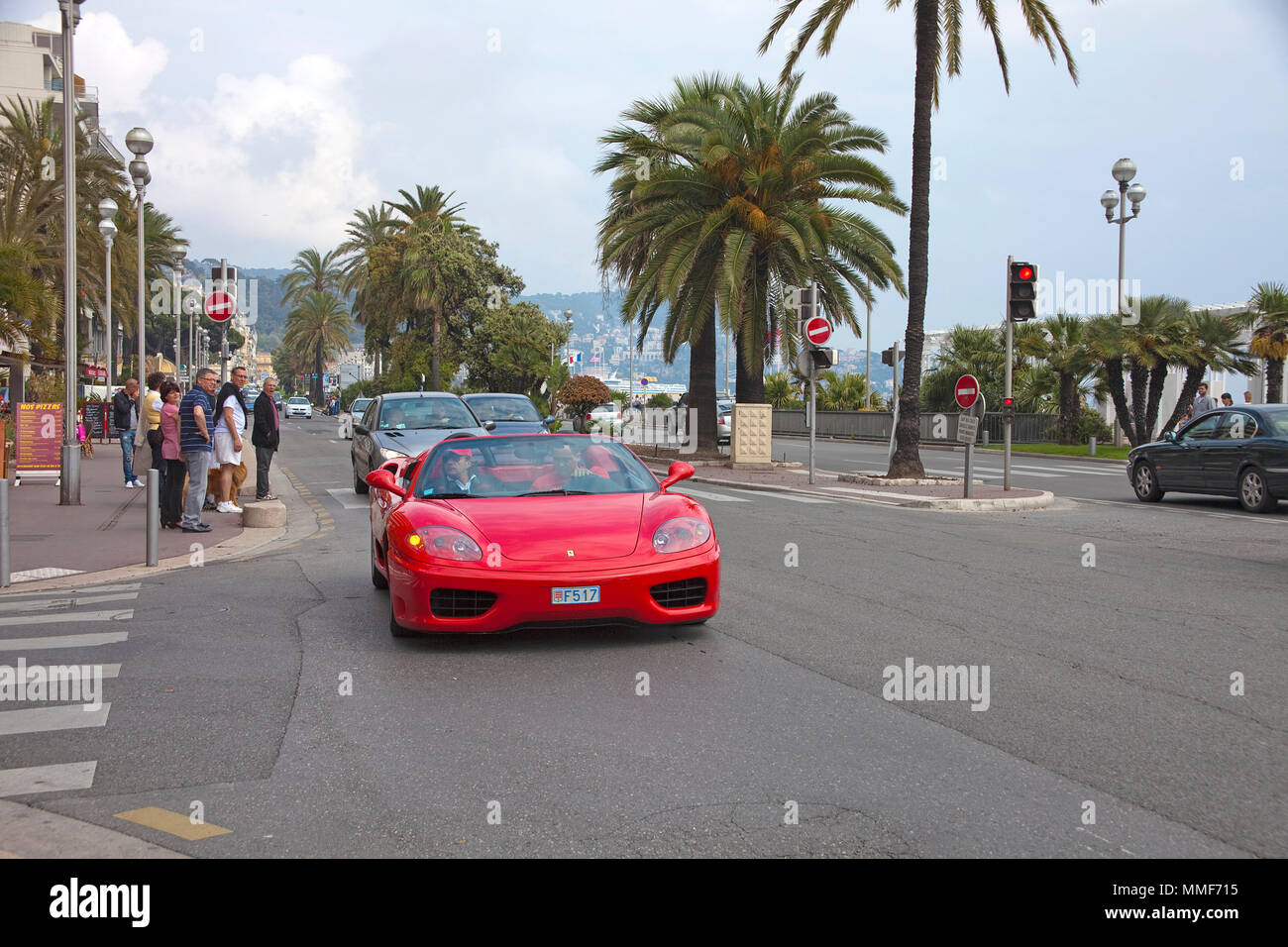 Red Ferrari driving on Promenade des Anglais, Côte d’Azur, Alpes-Maritimes, South France, France, Europe Stock Photo