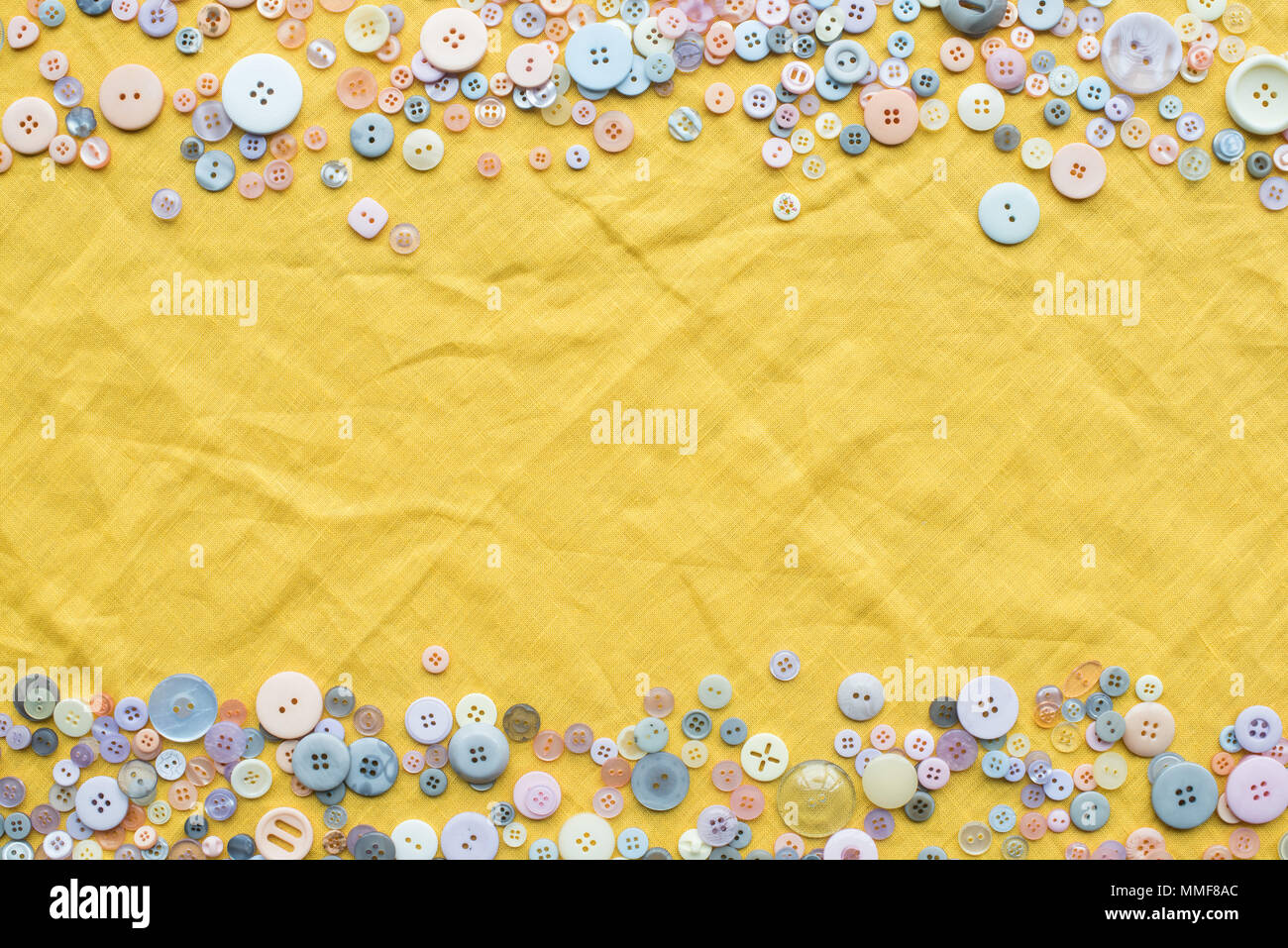 top view of colorful buttons frame on yellow cloth background with copy ...
