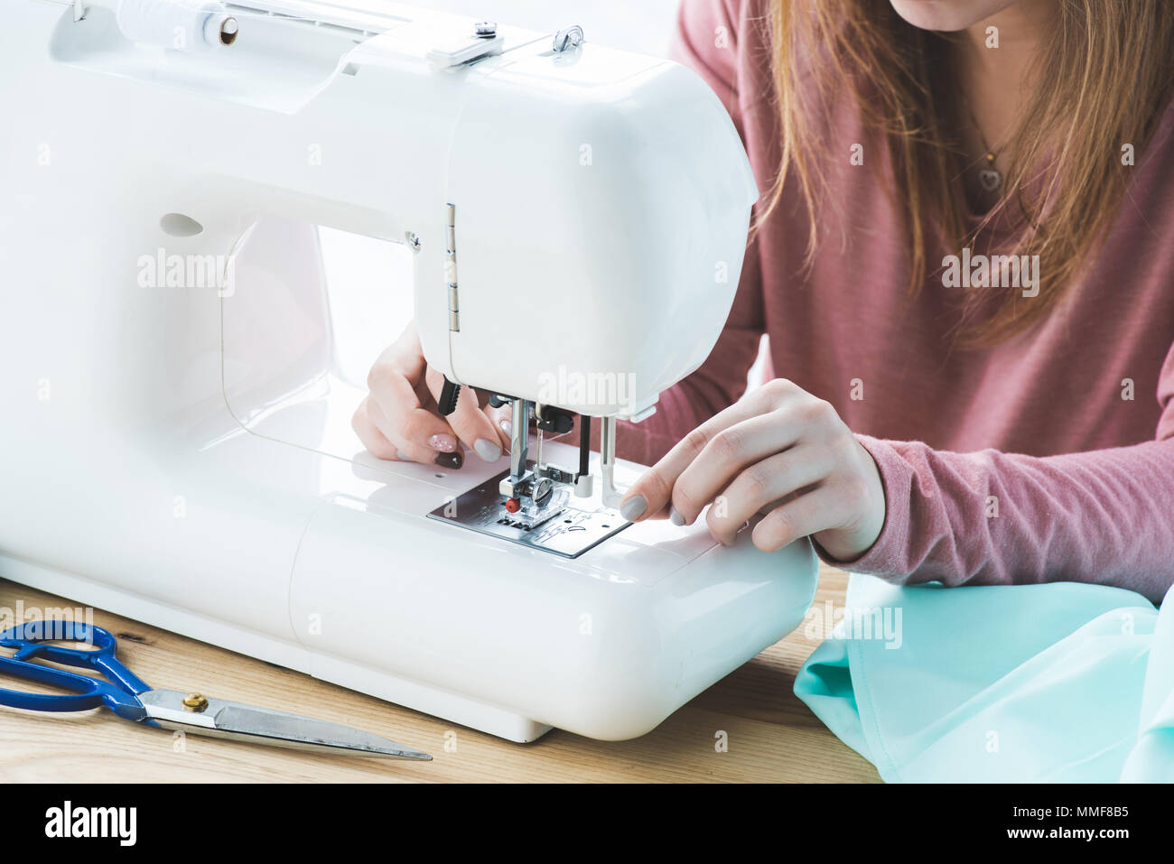 cropped image of young seamstress using sewing machine at workplace Stock Photo