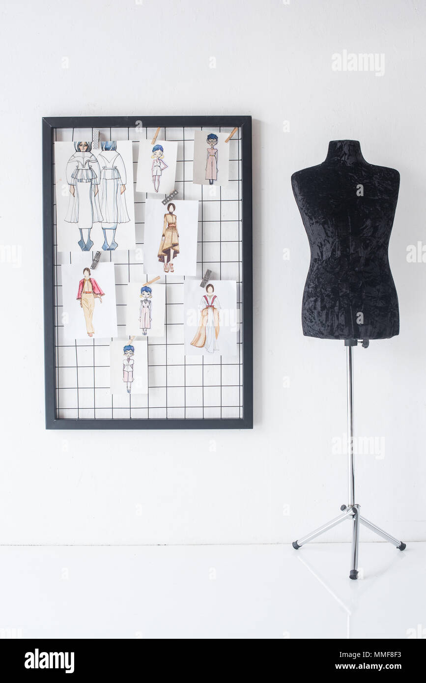 frame with fashion sketches hanged on white checkered background and black mannequin Stock Photo