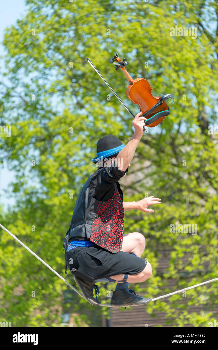 Tight Rope Playing Instruments portrait of Street performer walking tight rope and playing violin with ...