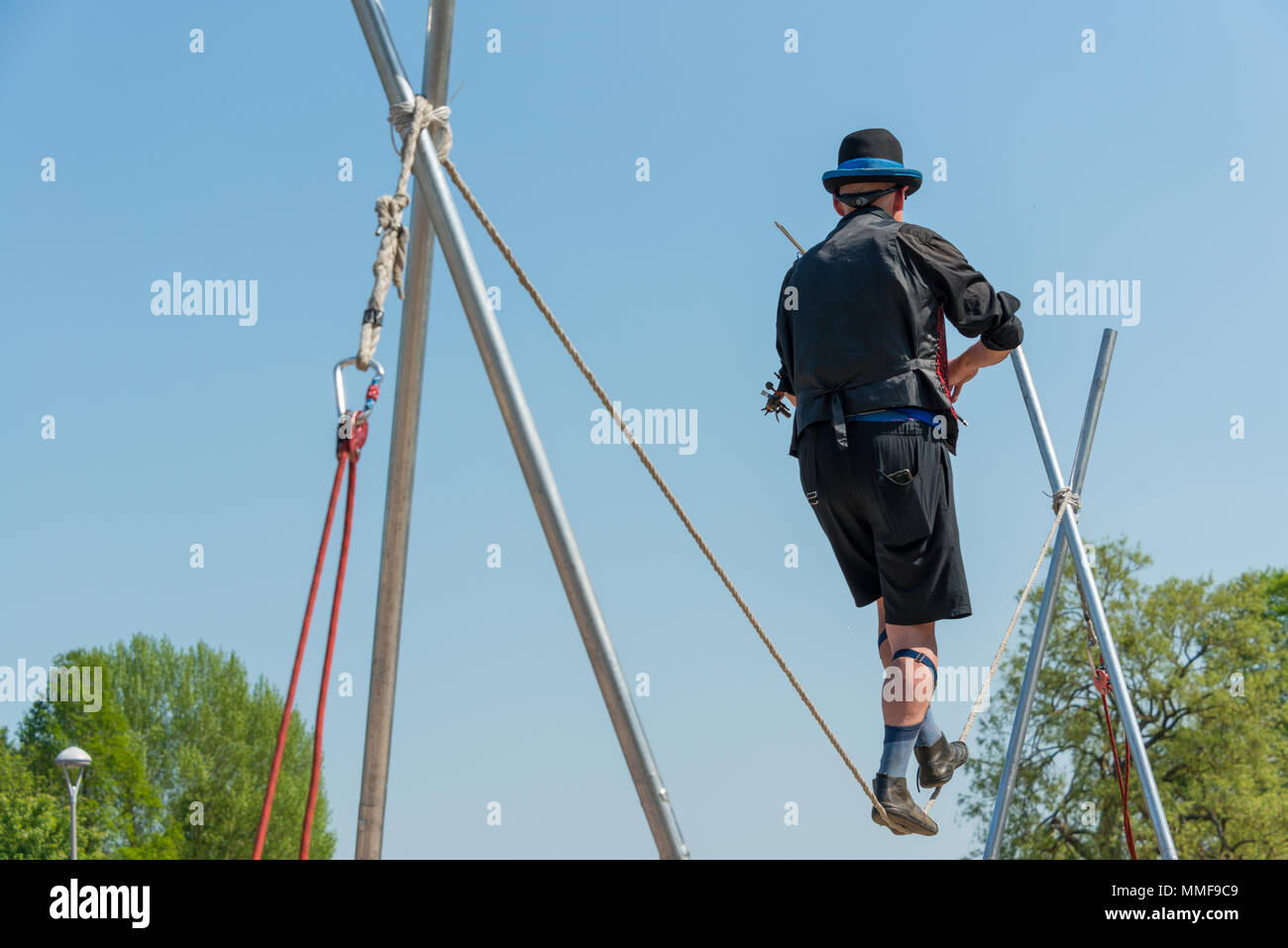 Tight Rope Playing Instruments rear view of Street performer walking tight rope and playing violin in ...