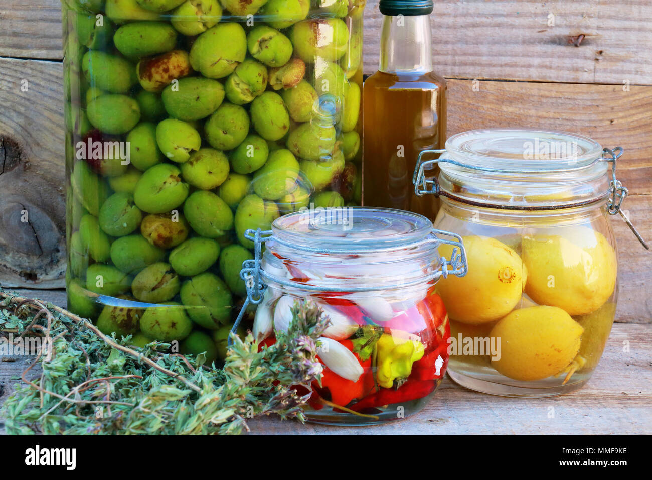Fermented vegetables in jars. Vegetarian food concept. Lemons, olives, peppers, chillies, olive oil, oregano Stock Photo