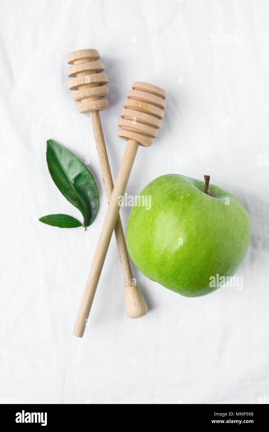 Wooden Honey Dippers Ripe Green Apple Leaves on White Cotton Linen Fabric Background. Organic Cosmetics Ayurveda Healthy Lifestyle Skin Care Concept.  Stock Photo