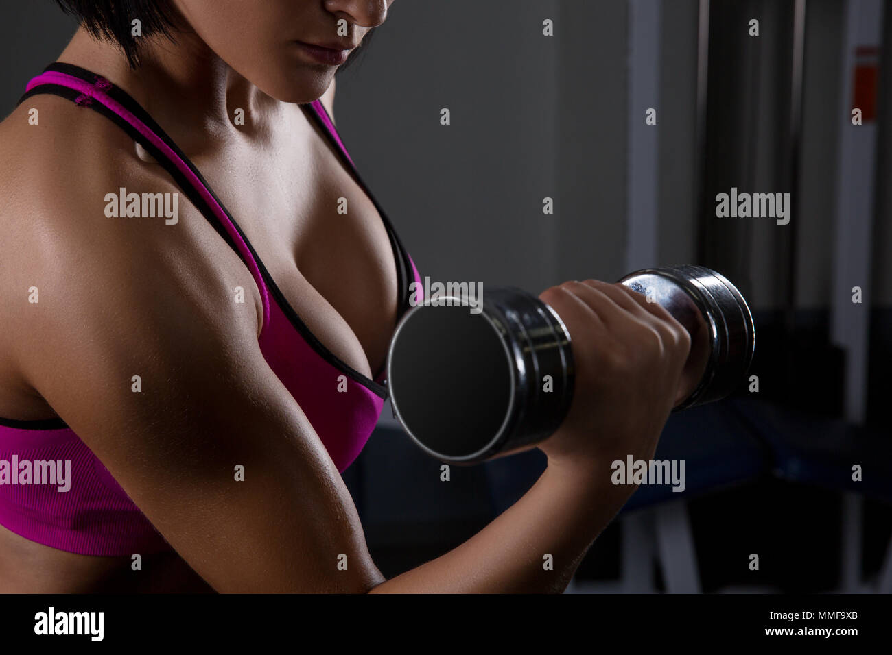 fitness model brunette holding weights on black background. athlete lifts a dumbbell. halthy concept Stock Photo