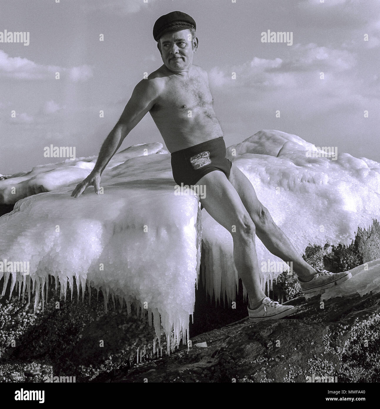 Man in bathing suit sitting on ice in Lake George, New York in the middle of winter. He is from the Polar Bear club from Coney Island in the 1980s Stock Photo