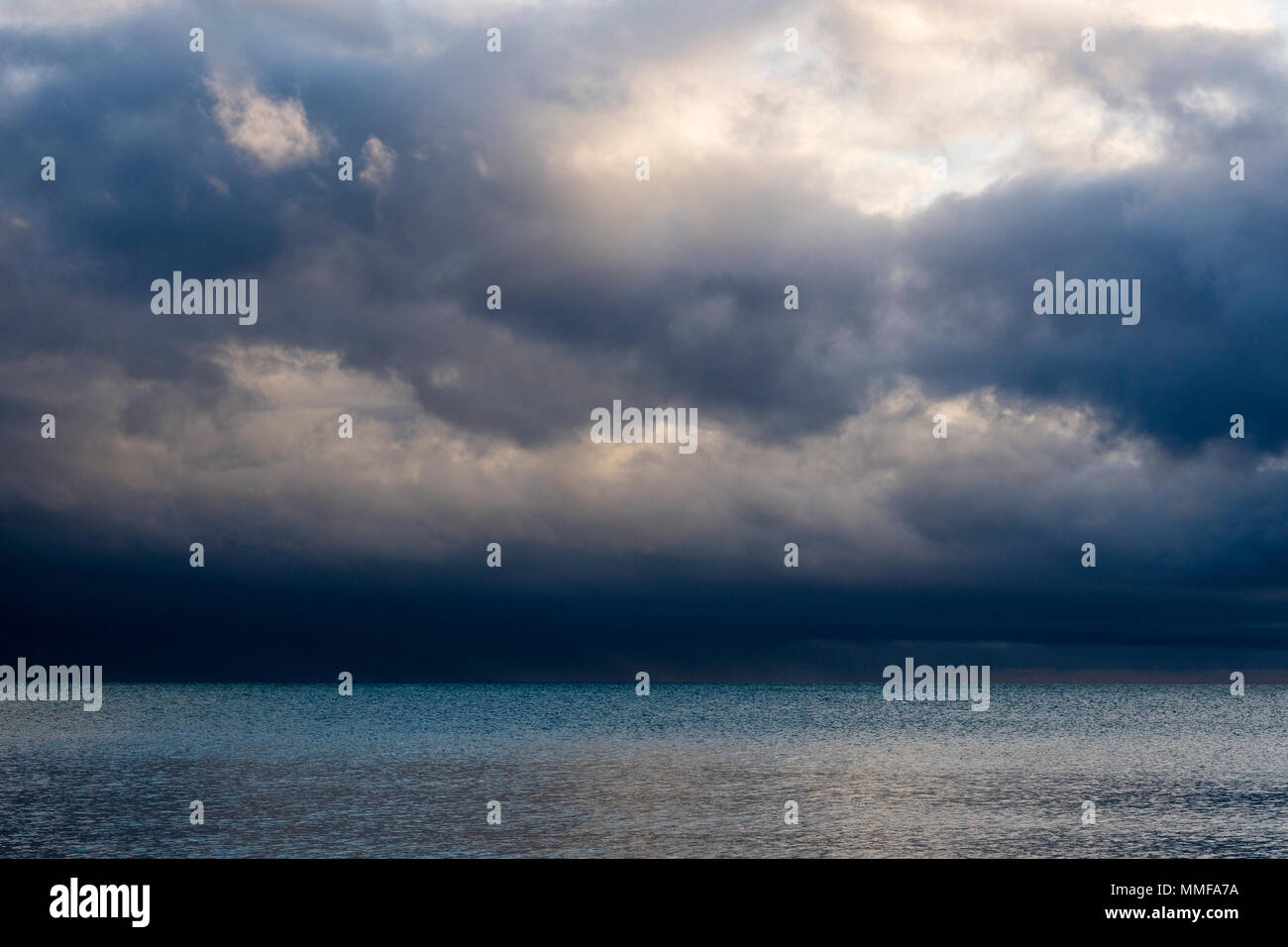 Storm clouds reflected in a calm tropical ocean at dawn. Stock Photo