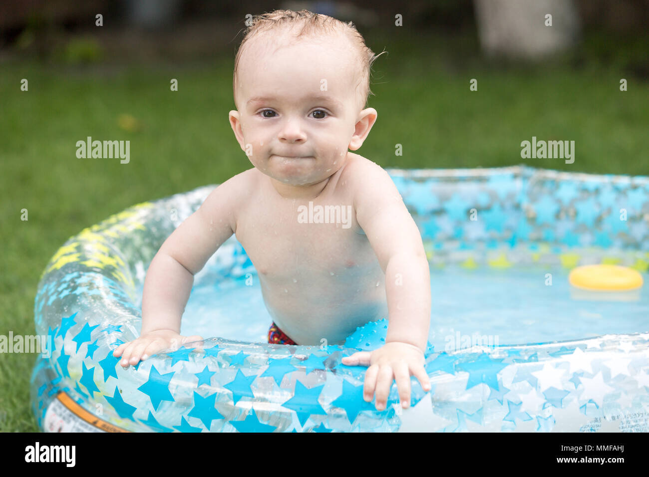 Portrait of cute 10 months old baby boy enjoying swimming in inflatable
