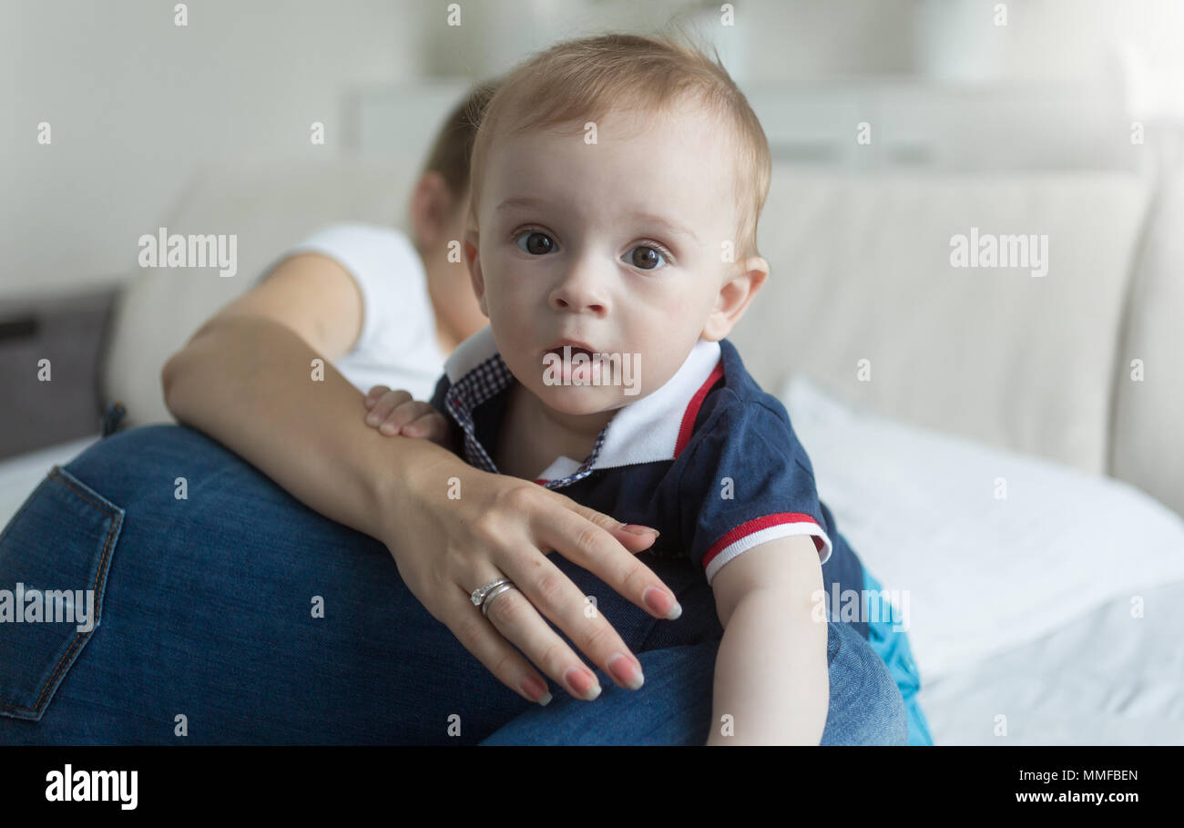 Portrait of 10 months old baby boy crawling over mother lying in bed