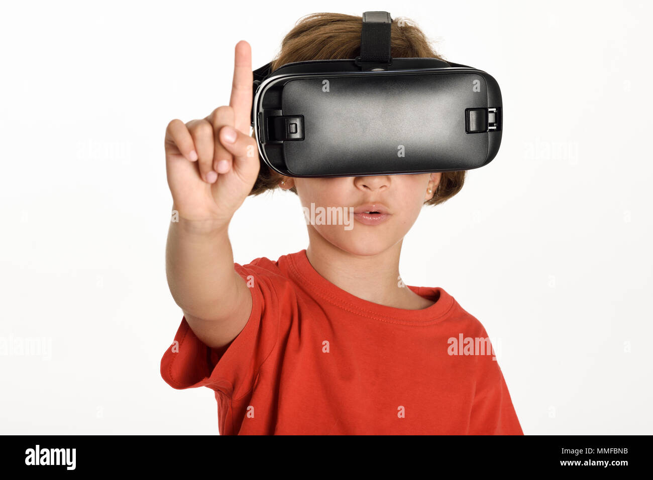 Little girl looking in VR glasses and gesturing with his hands. Cheerful surprised child wearing virtual reality goggles watching movies or playing vi Stock Photo