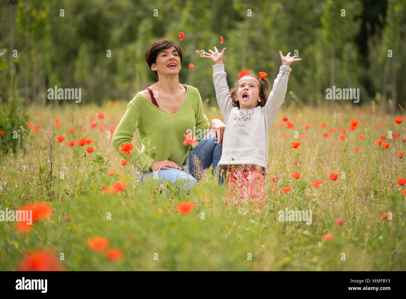 Happy mother with her little daughter in poppy field Stock Photo