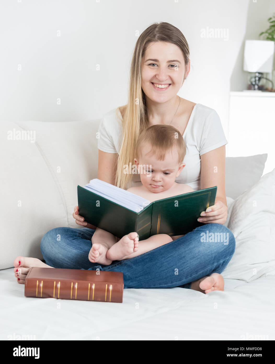 Portrait of cute baby boy sitting on mothers lap and reading big book