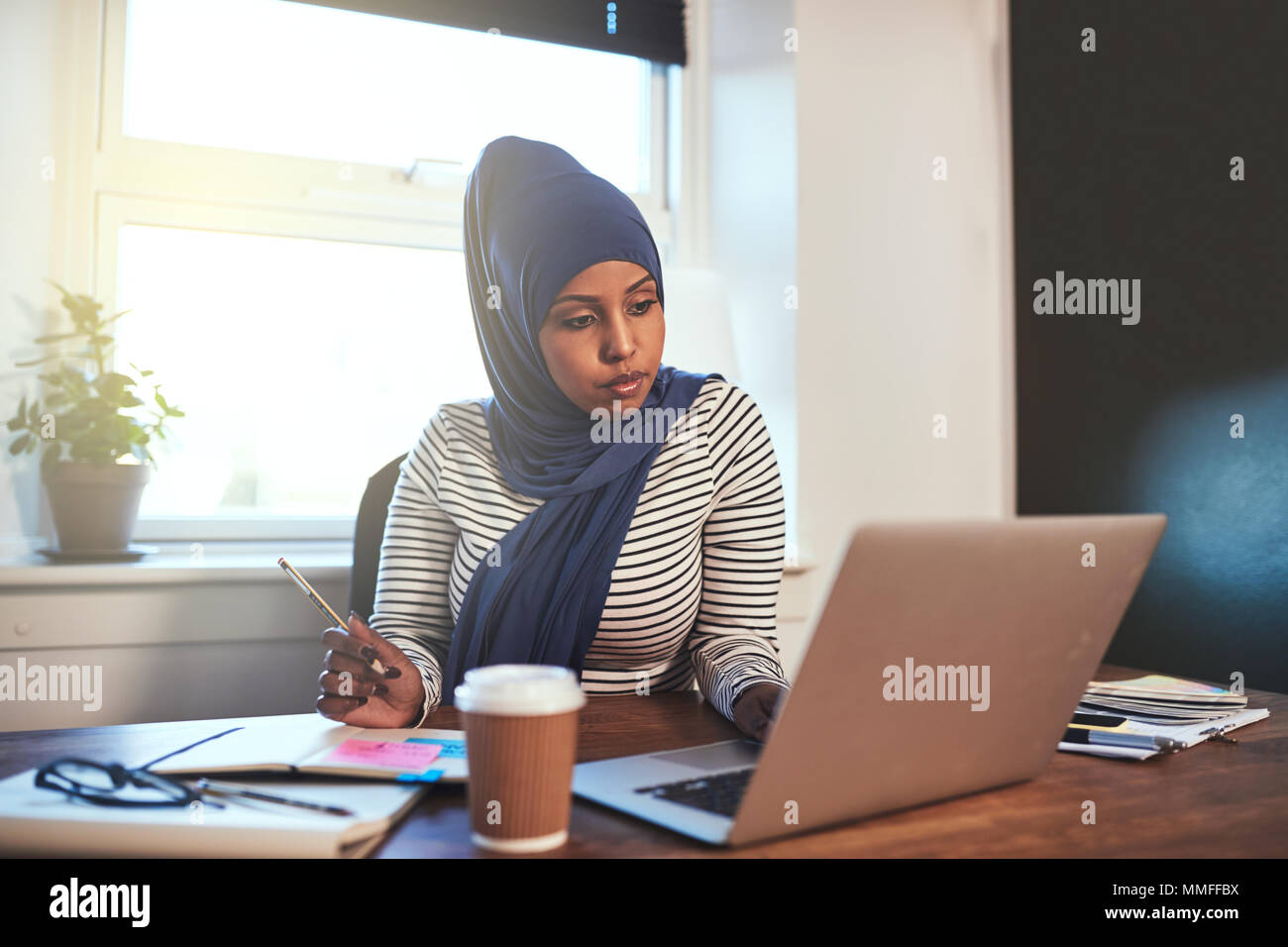 Young Arabic female entrepreneur wearing a hijab working online with a ...