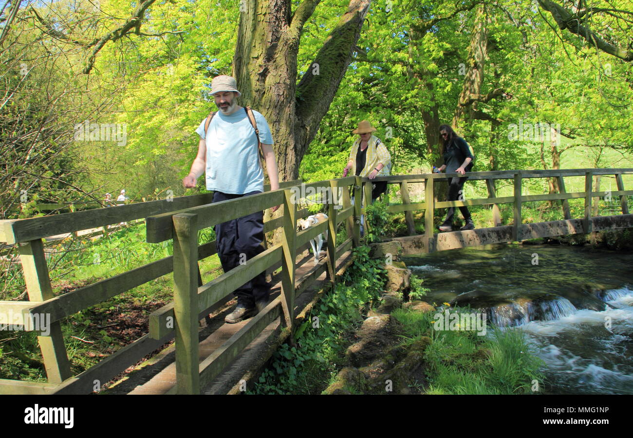 Walkers on a bridge over the River Dove at Beresford Dale near Hartington, Peak District, Derbyshire Dales, England UK in mid spring Stock Photo