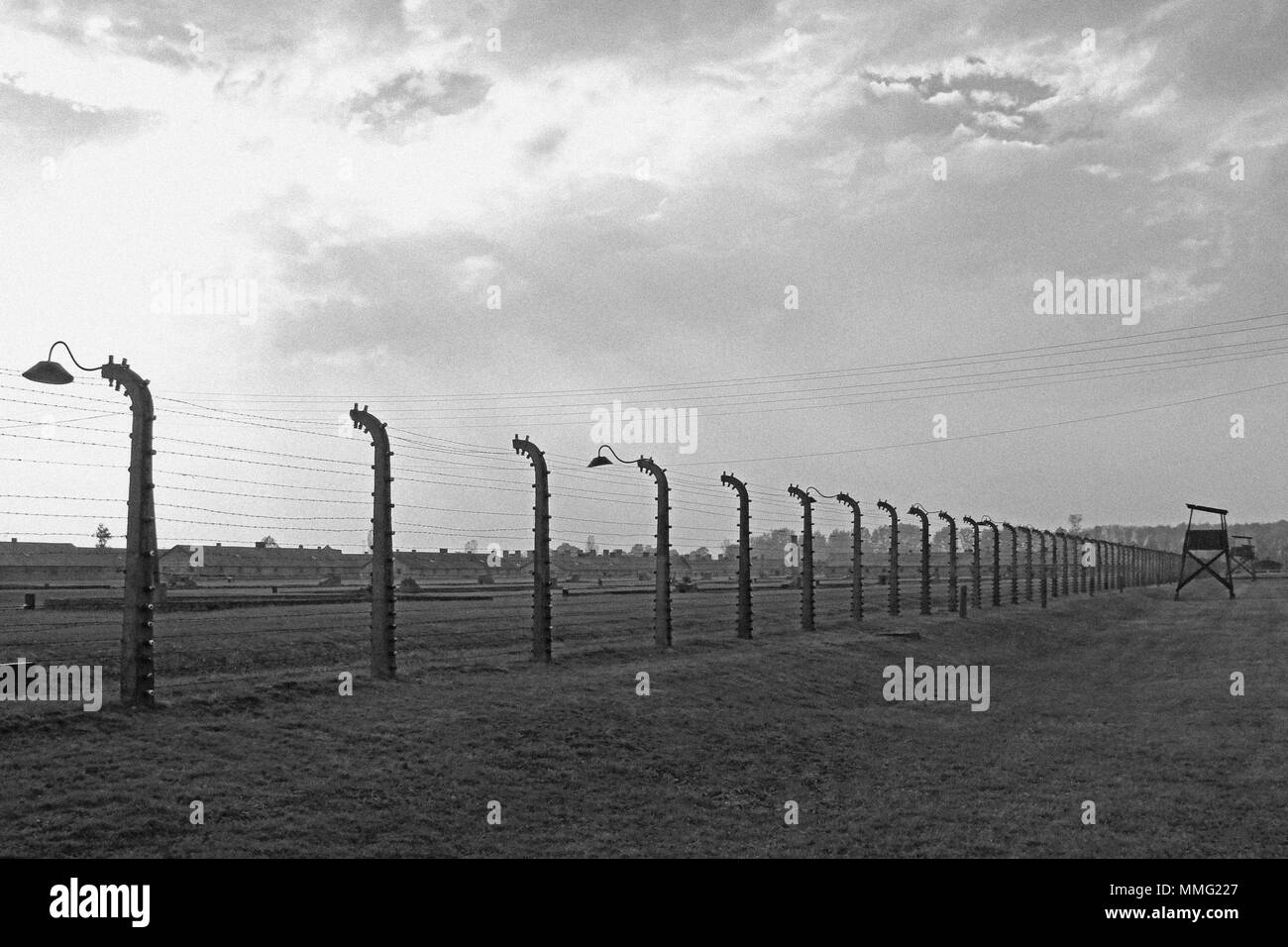 AUSCHWITZ, POLAND, OCTOBER 12, 2013: Fence and watchtower at concentration camp at Auschwitz Birkenau KZ, black and white photography with image noise effect, Poland Stock Photo